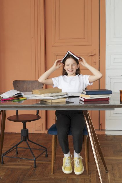 full-shot-smiley-girl-sitting-desk