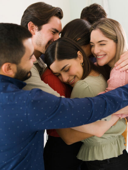 Offering support to the new members of a rehab group. Young people hugging and feeling proud and happy during a therapy session