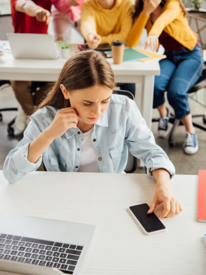 schoolchildren laughing while bullying sad girl on foreground